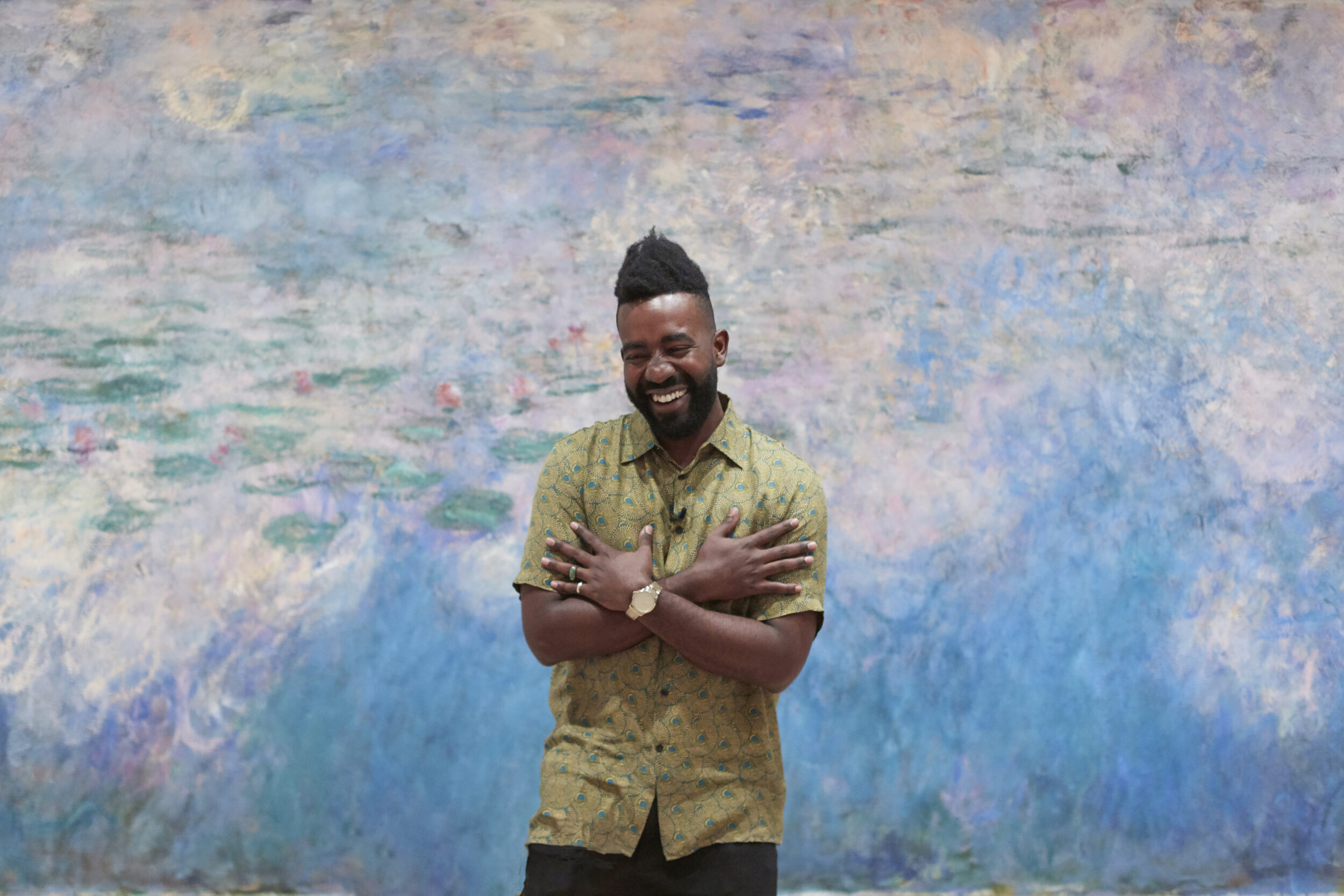 Security guard smiles in a thank you posture in front of Monet's Water Lilies painting at MoMA