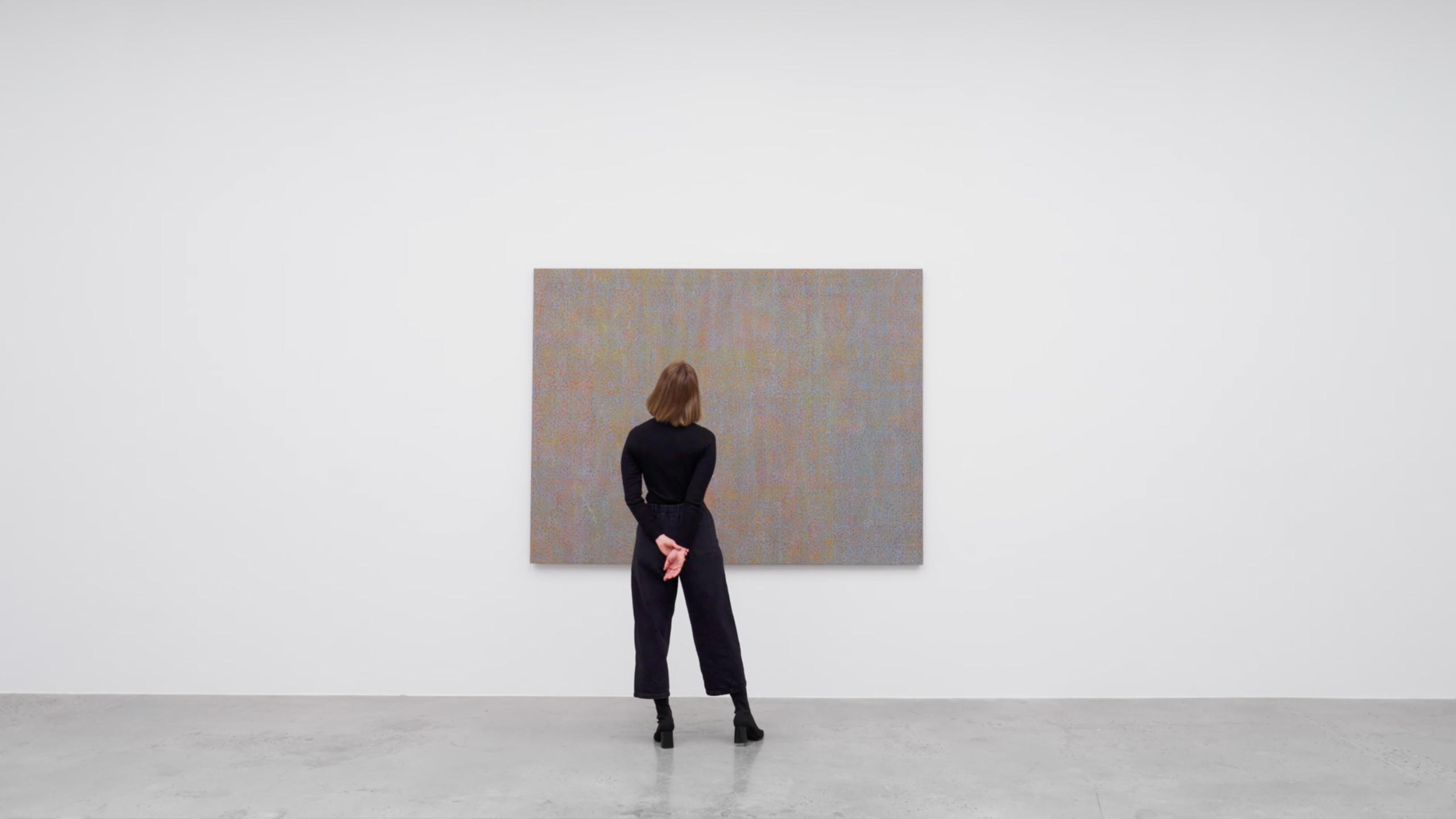 A viewer in front of a painting by Howardena Pindell