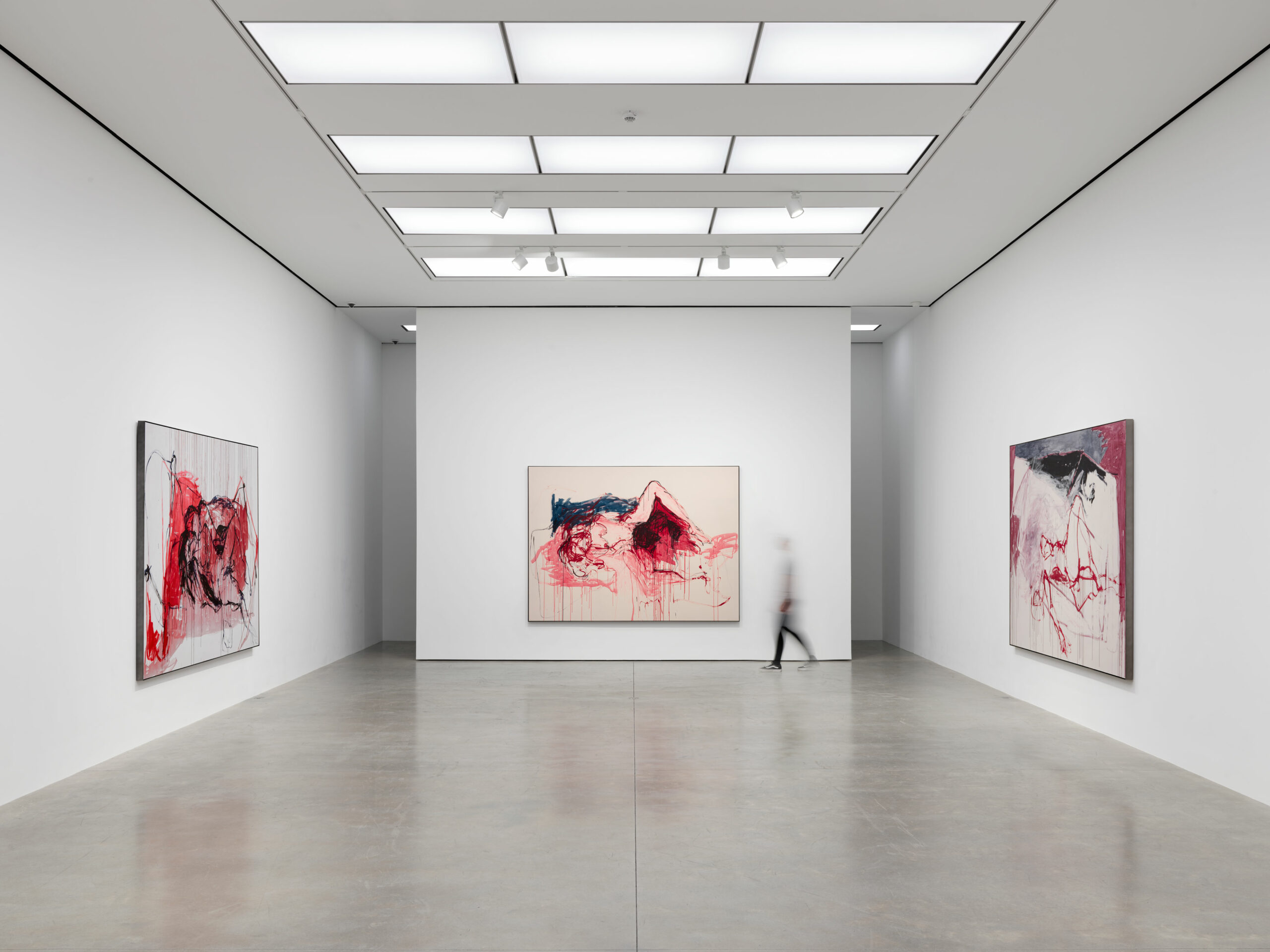 Installation view of contemporary art gallery with 3 large colorful paintings and a walking visitor.