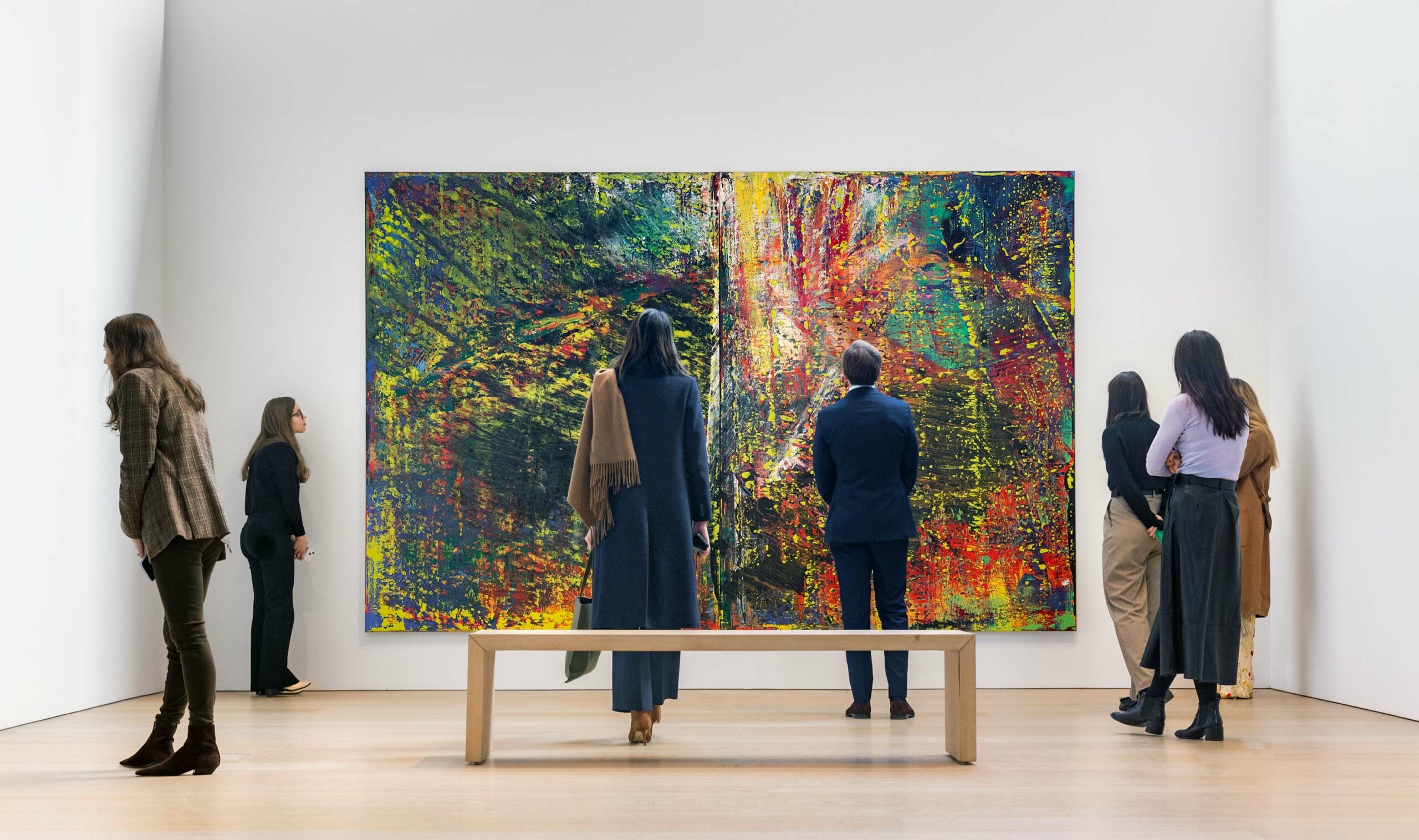 Exhibition view of several viewers in front of a large abstract colorful painting by Gerard Richter.