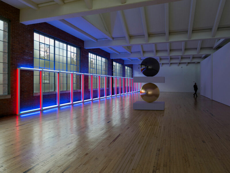 3D visualization of a reflective sculpture composed of 2 spheres installed next to a large red and blue neon artwork by Dan Flavin in Dia Beacon, NY.