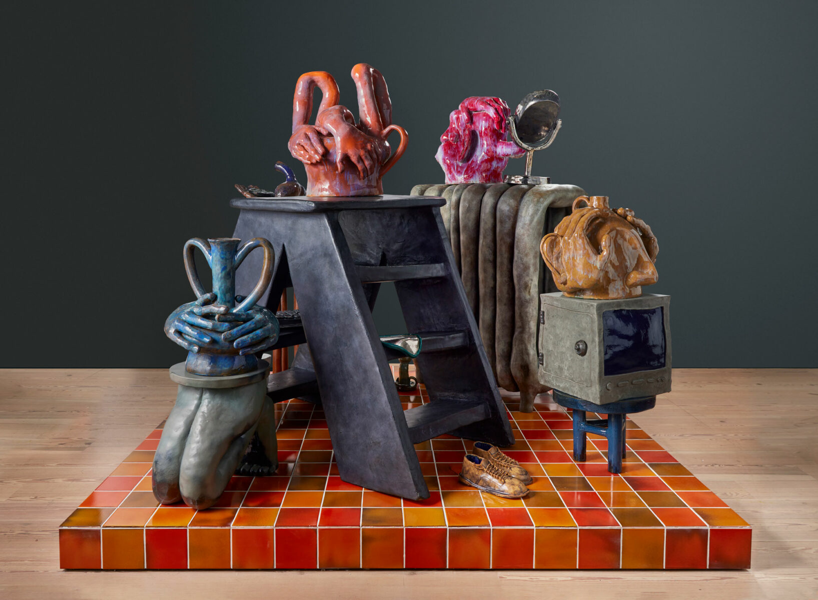 Ceramic sculpture of oversize common day objects such a TV, mirror, radiator and ladder.